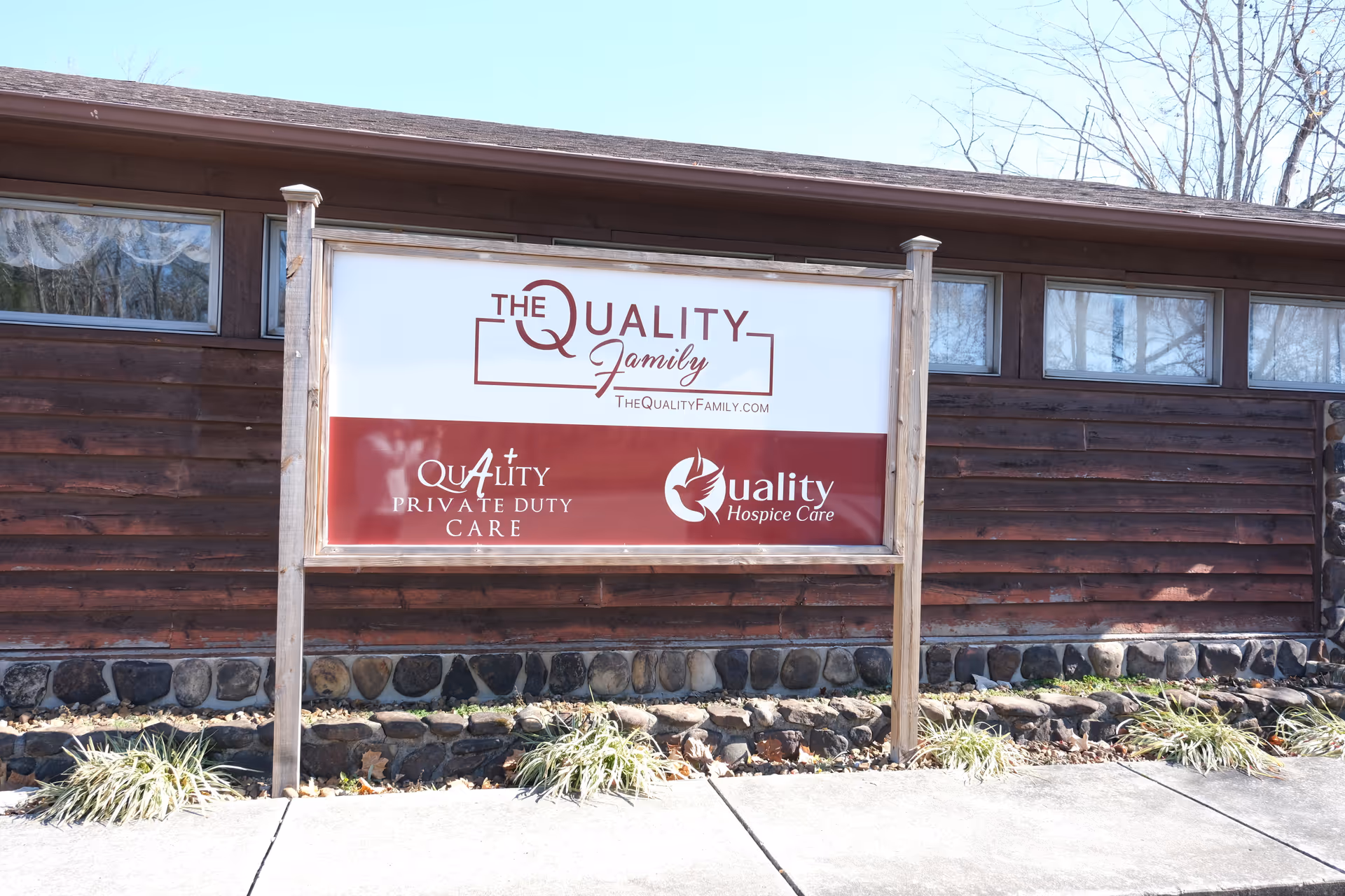 A wooden building exterior featuring a large sign for The Quality Family and related logos.