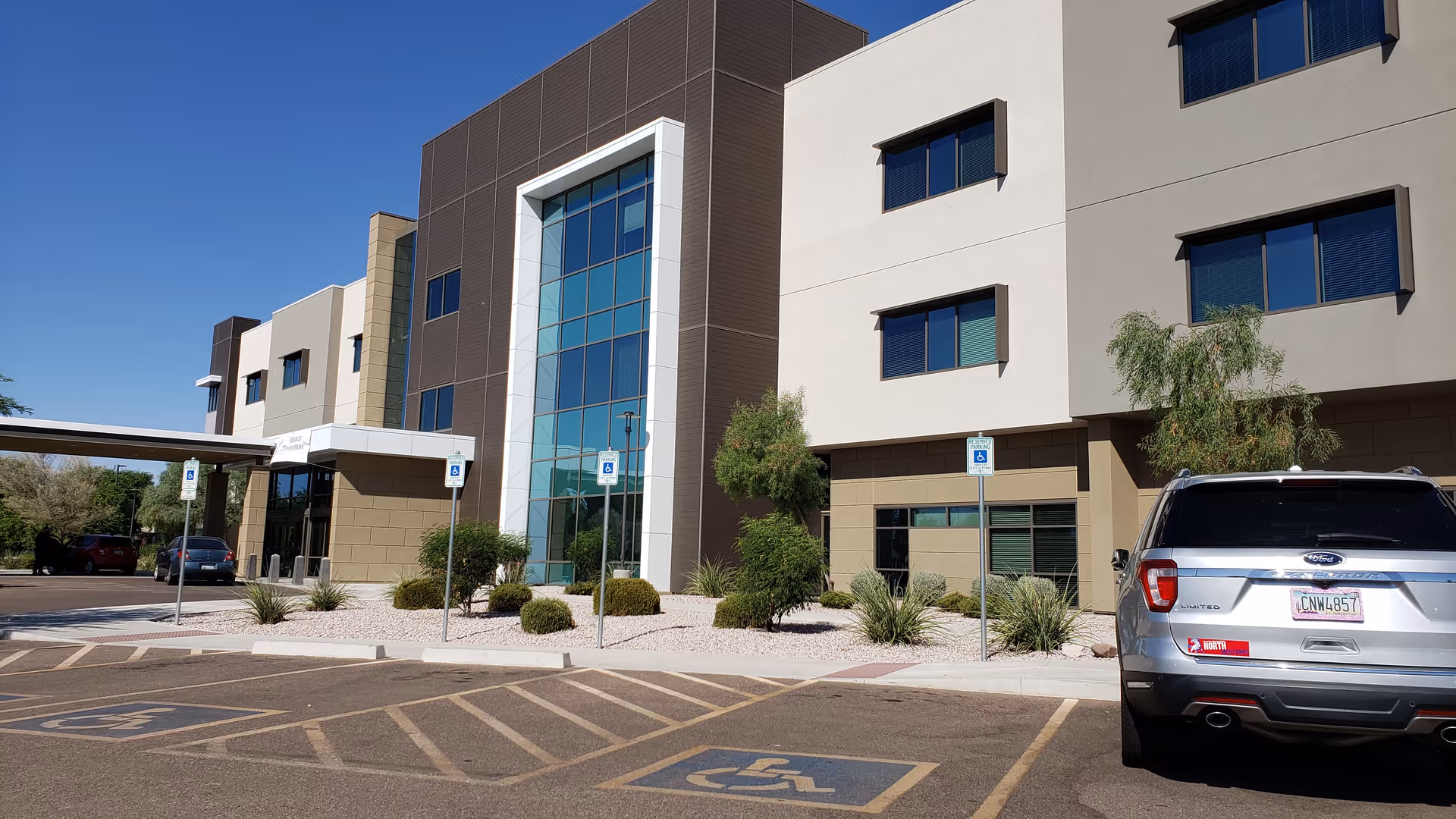 Modern senior living facility exterior with parking, handicap spaces, and desert landscaping.
