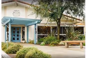 Exterior view of Pacific Coast Manor entrance with blue doors and landscaping