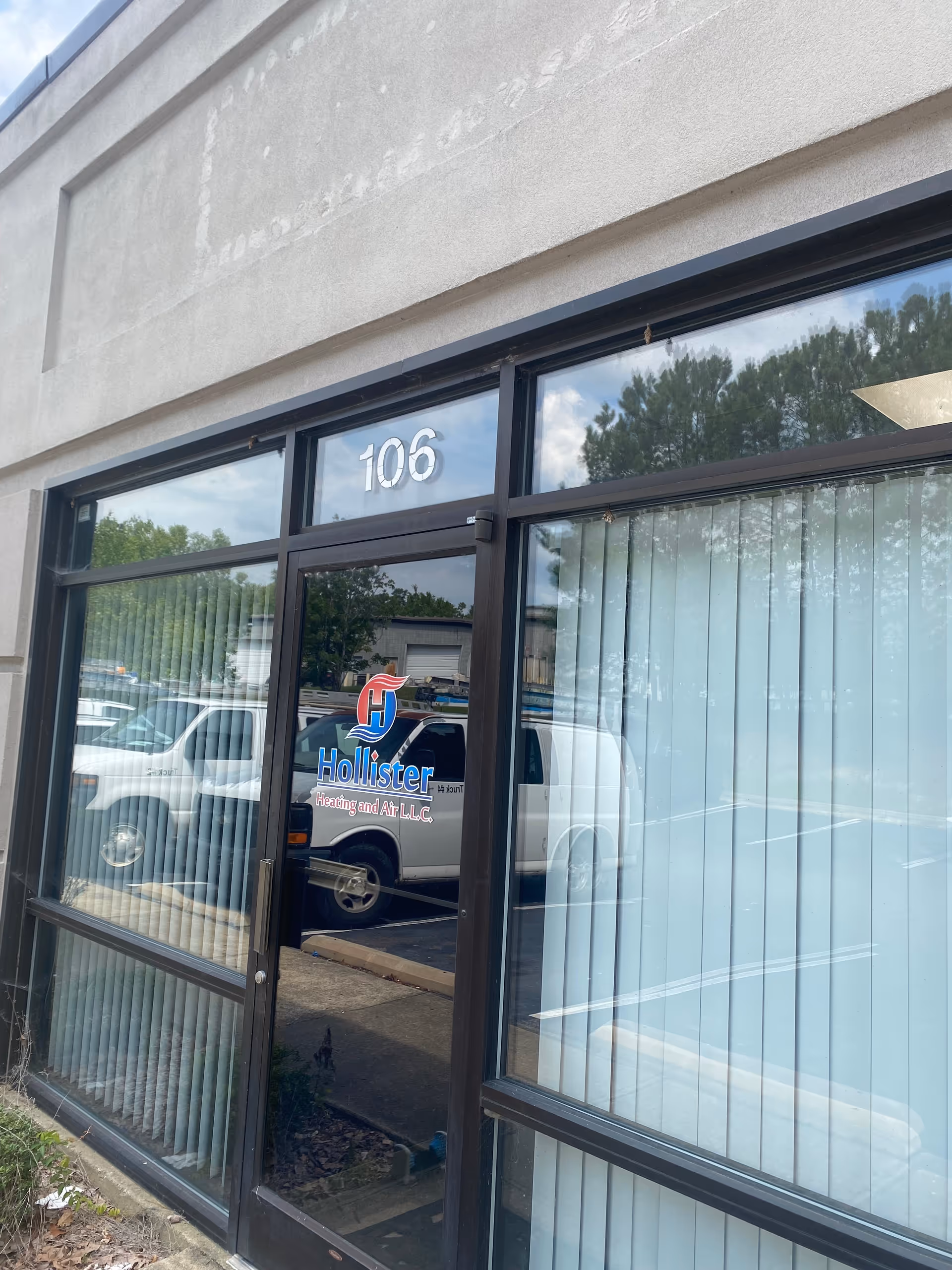 Exterior entrance with glass doors marked 106, reflecting parked vehicles.