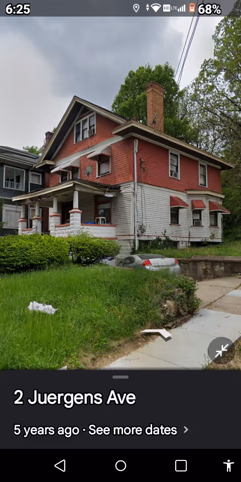 Front view of Vine Street House, a two-story red-brick and white-siding building with a front porch.