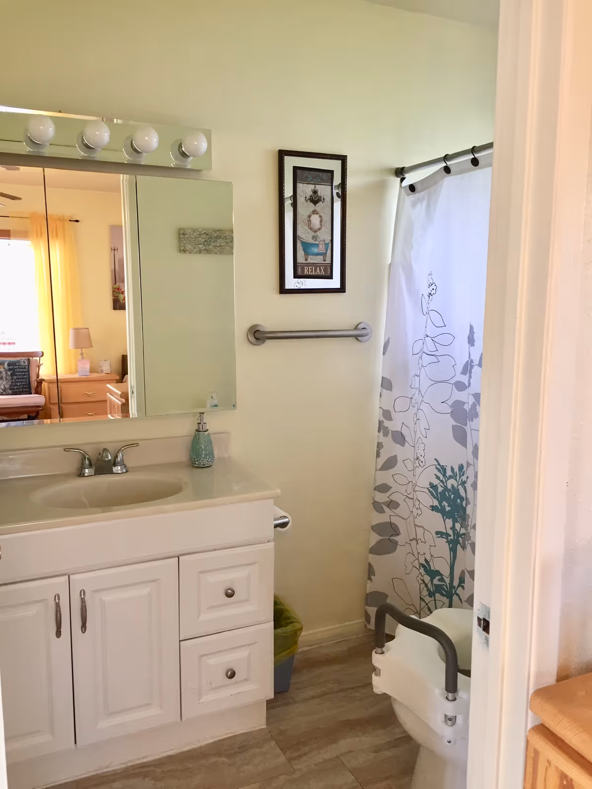 Bathroom with sink, mirror, lighted vanity, towel bar, shower curtain, and accessible toilet.