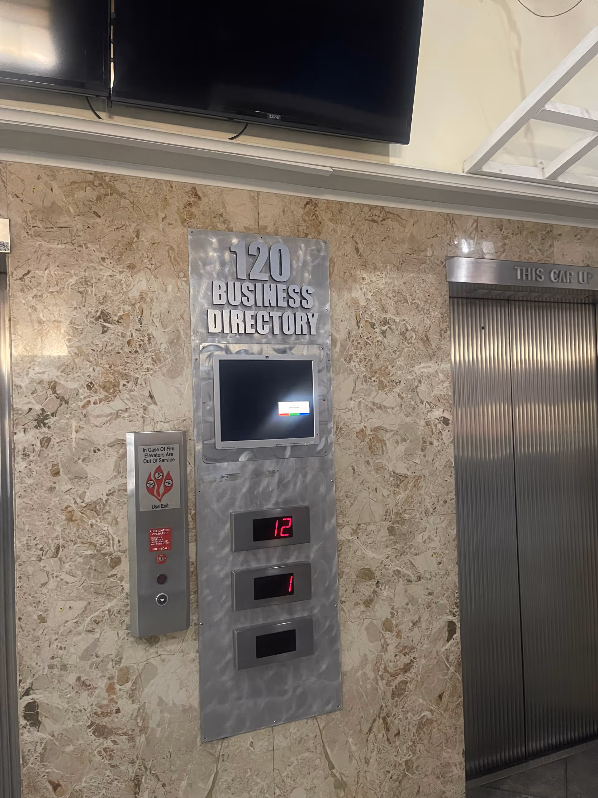 Marble-clad lobby with a 120 Business Directory sign and elevator panel.