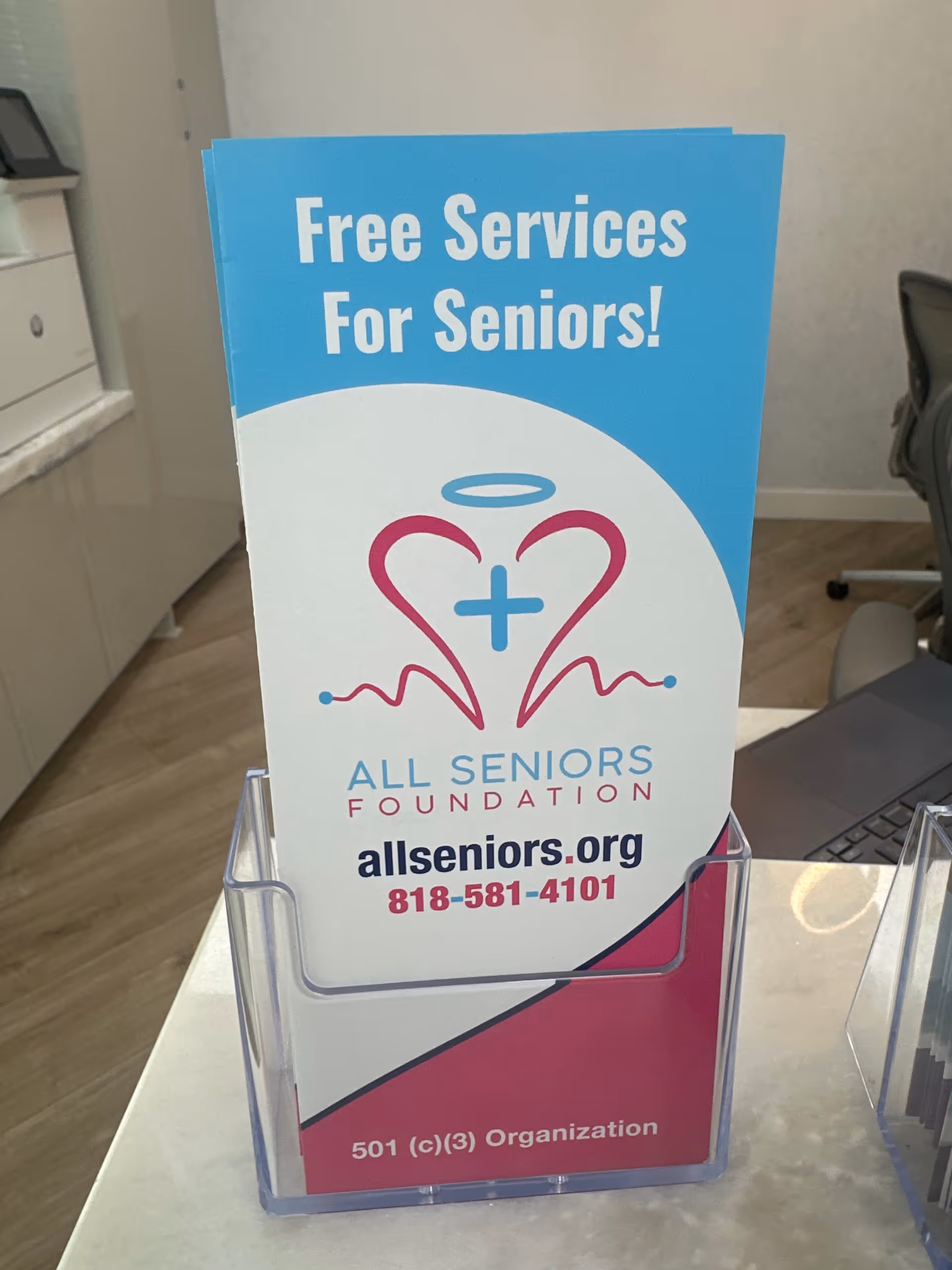 Blue brochure for Free Services For Seniors at All Seniors Foundation on desk.