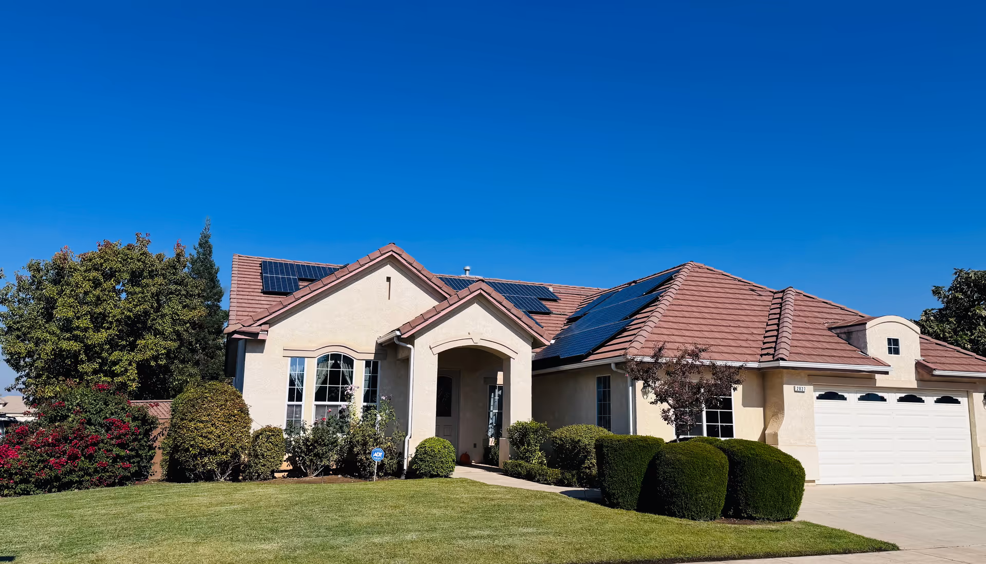 Residential care facility front: single-story beige house with red tile roof and solar panels.