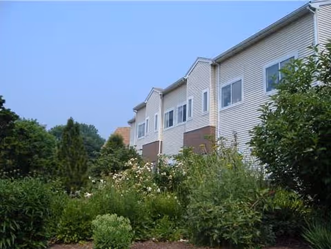 Exterior view of a multi-unit senior living building with lush landscaping.