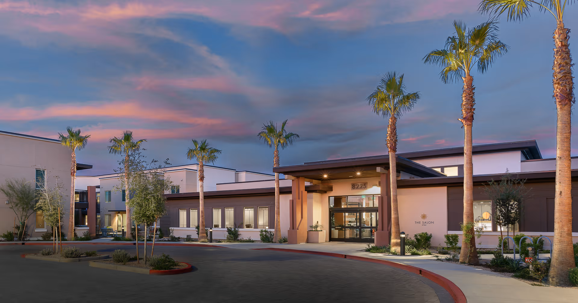 Exterior view of Revel Scottsdale entrance with palm trees and sunset sky.