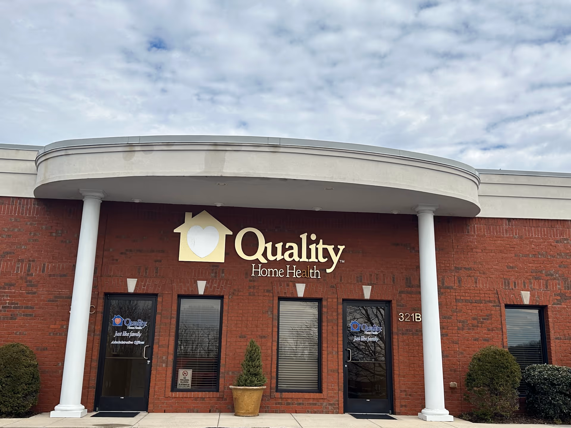 Brick building with curved white awning and Quality Home Health Care sign.