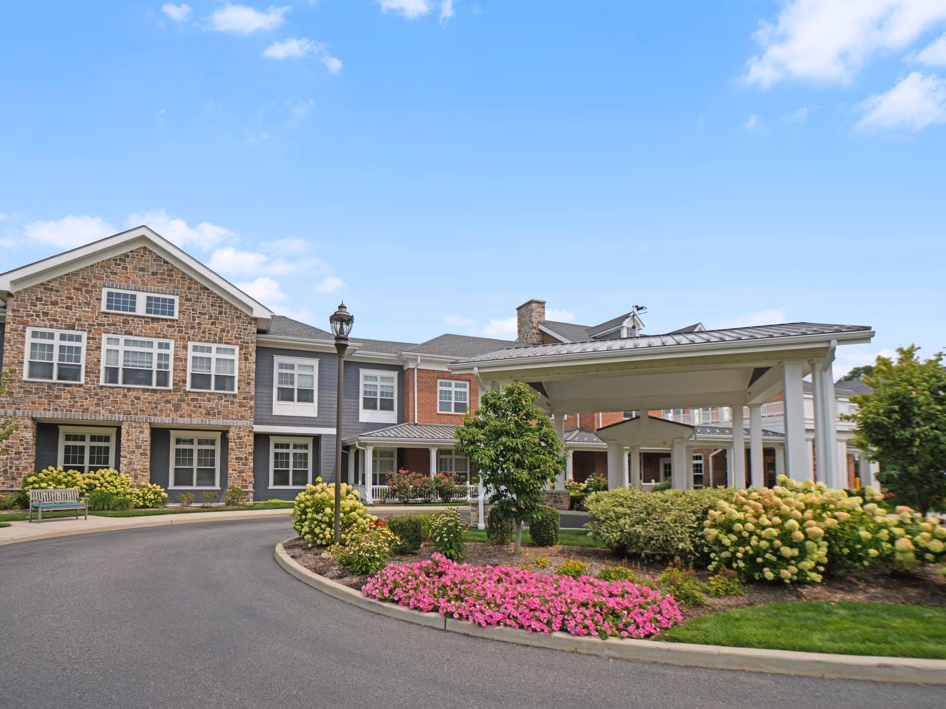 Exterior view of Sunrise of Huntington with landscaped roundabout and covered entrance.