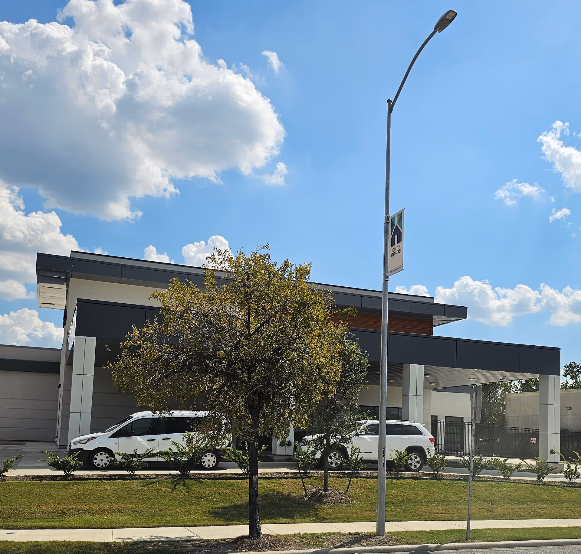 Modern VA facility exterior with trees, vehicles, and a streetlight.