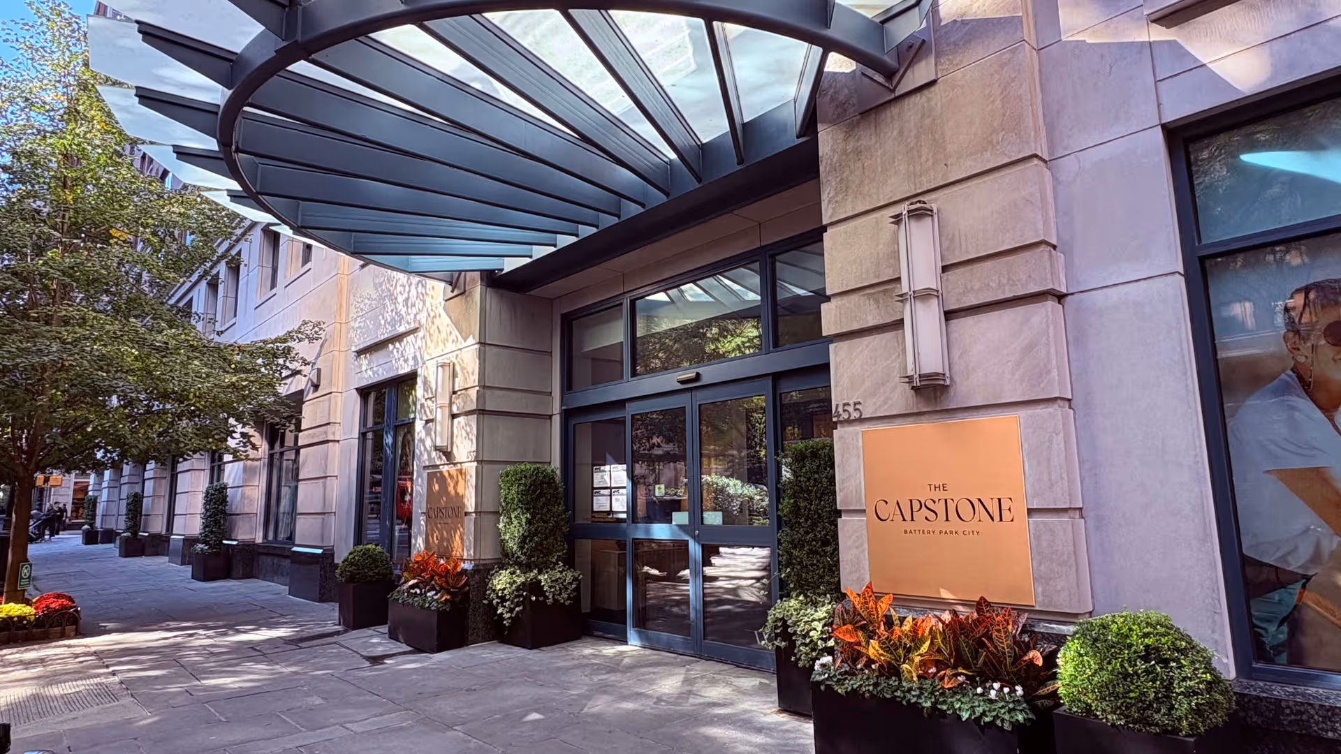Exterior view of a modern building entrance with glass doors and planters.