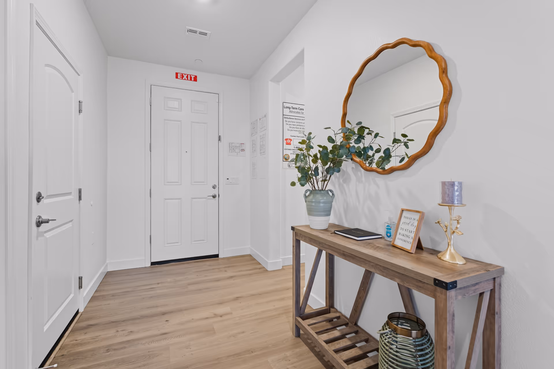 Hallway interior with white walls, doors, and a wooden console table beside a round mirror.
