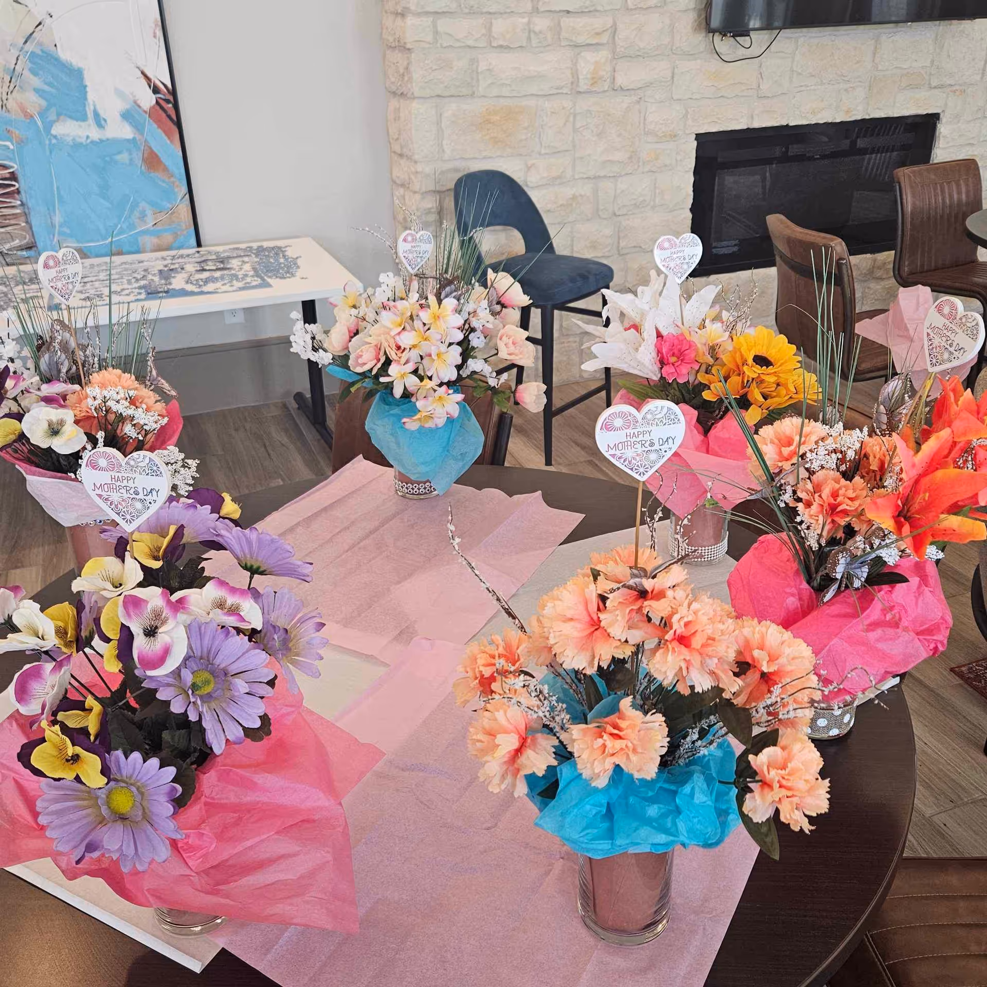 Indoor common area with colorful flower bouquets on pink-covered tables.