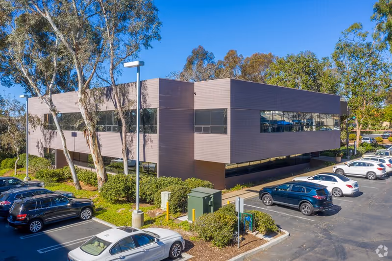 Modern two-story Elite Home Care facility with large windows, surrounded by parking and trees.