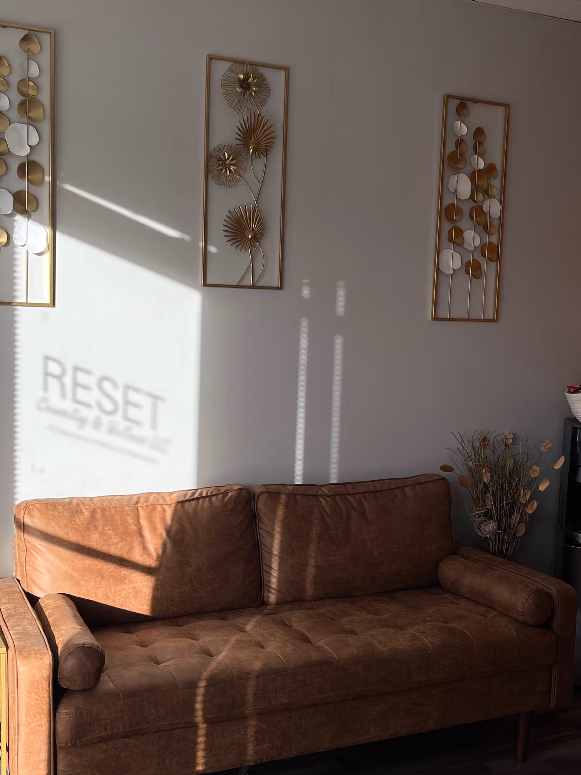 Brown leather sofa in a softly lit living room with abstract wall art decor.