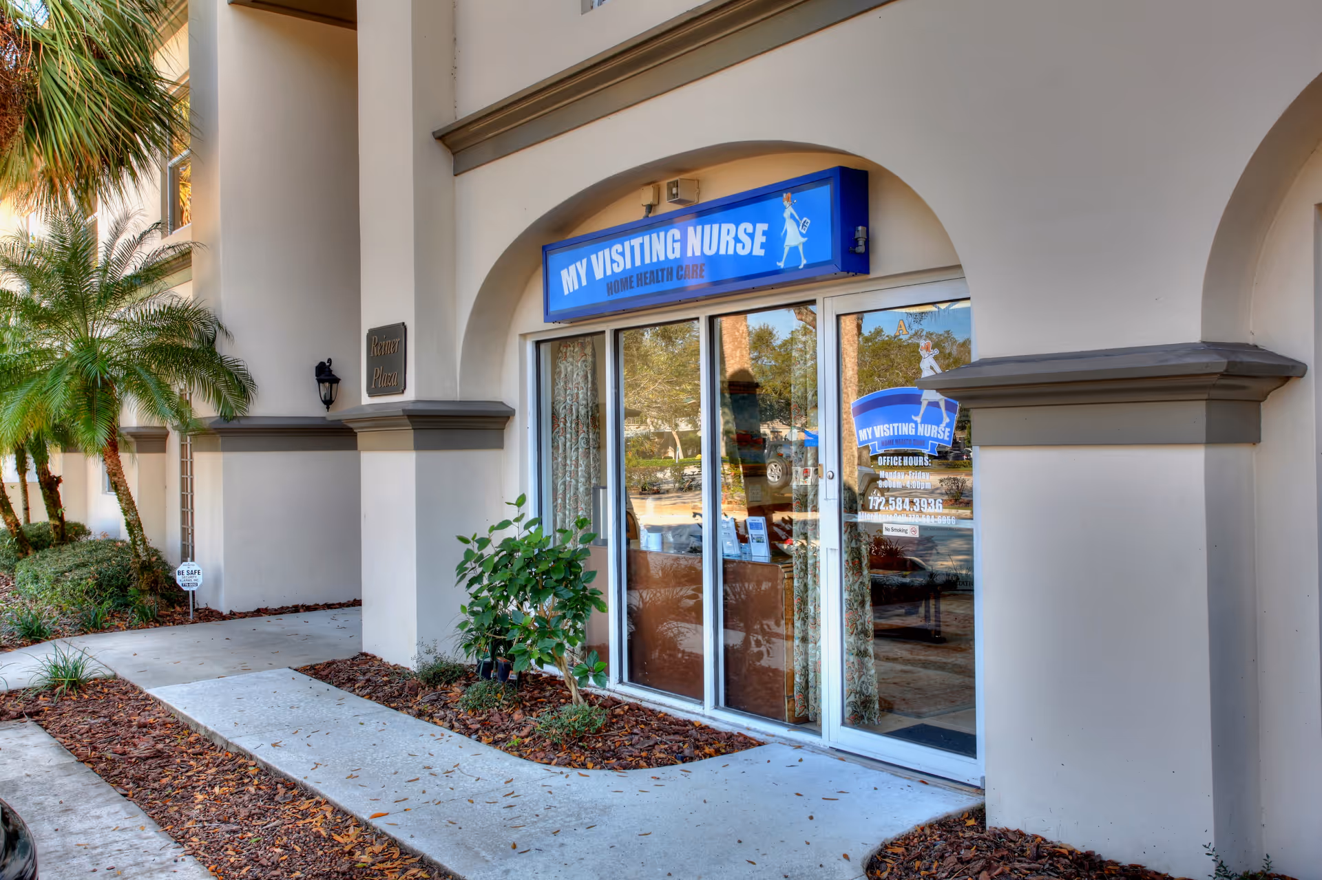 Exterior storefront with blue My Visiting Nurse sign and glass entrance under arches.