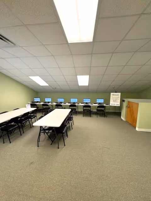 An interior conference room with long tables and chairs facing monitors.