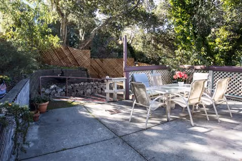 Outdoor patio with a table, chairs, potted plants, and surrounding trees