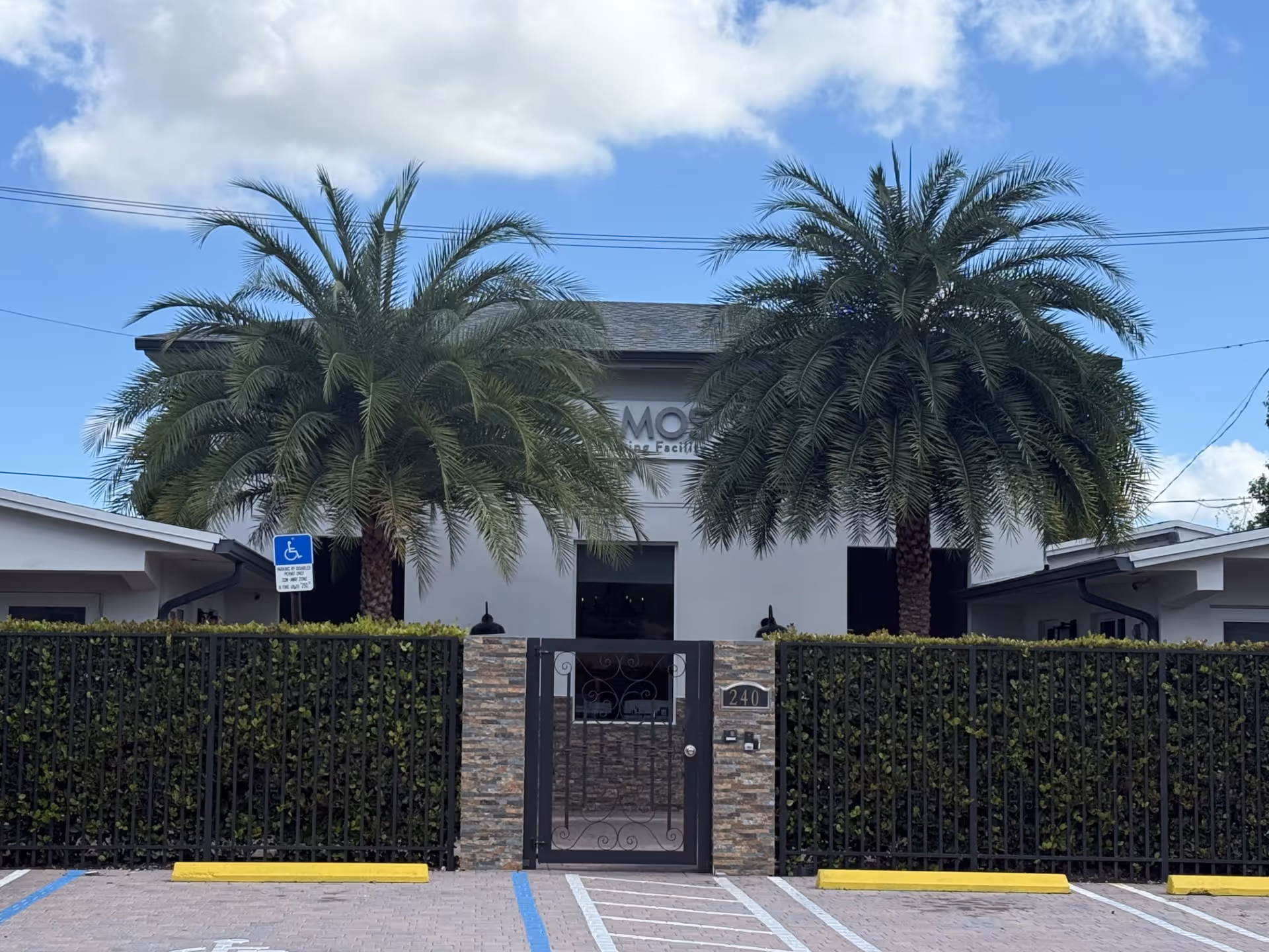 Exterior view of Salmos 23 V senior facility with a gated entrance and palms.
