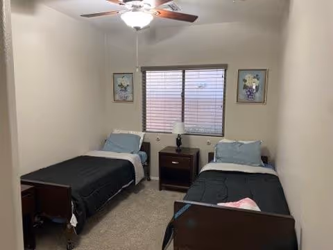 Two single beds with matching dark bedding sit in a small shared bedroom.