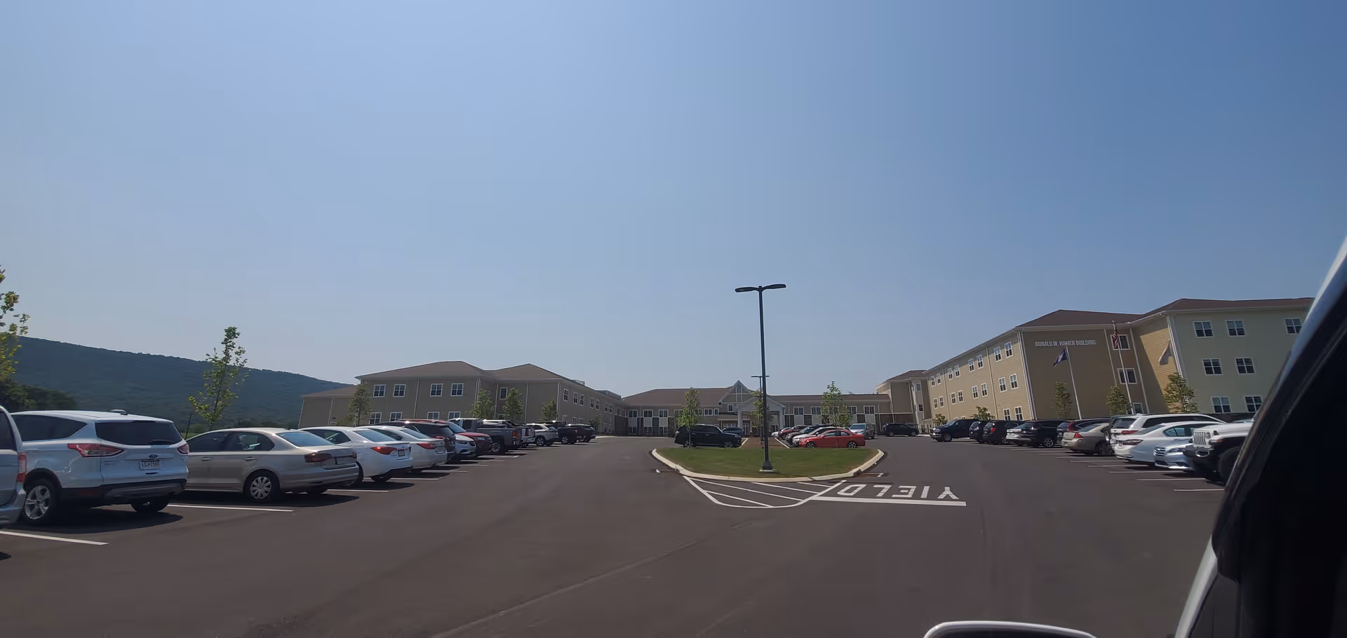 Parking lot and beige senior living buildings under a clear blue sky.