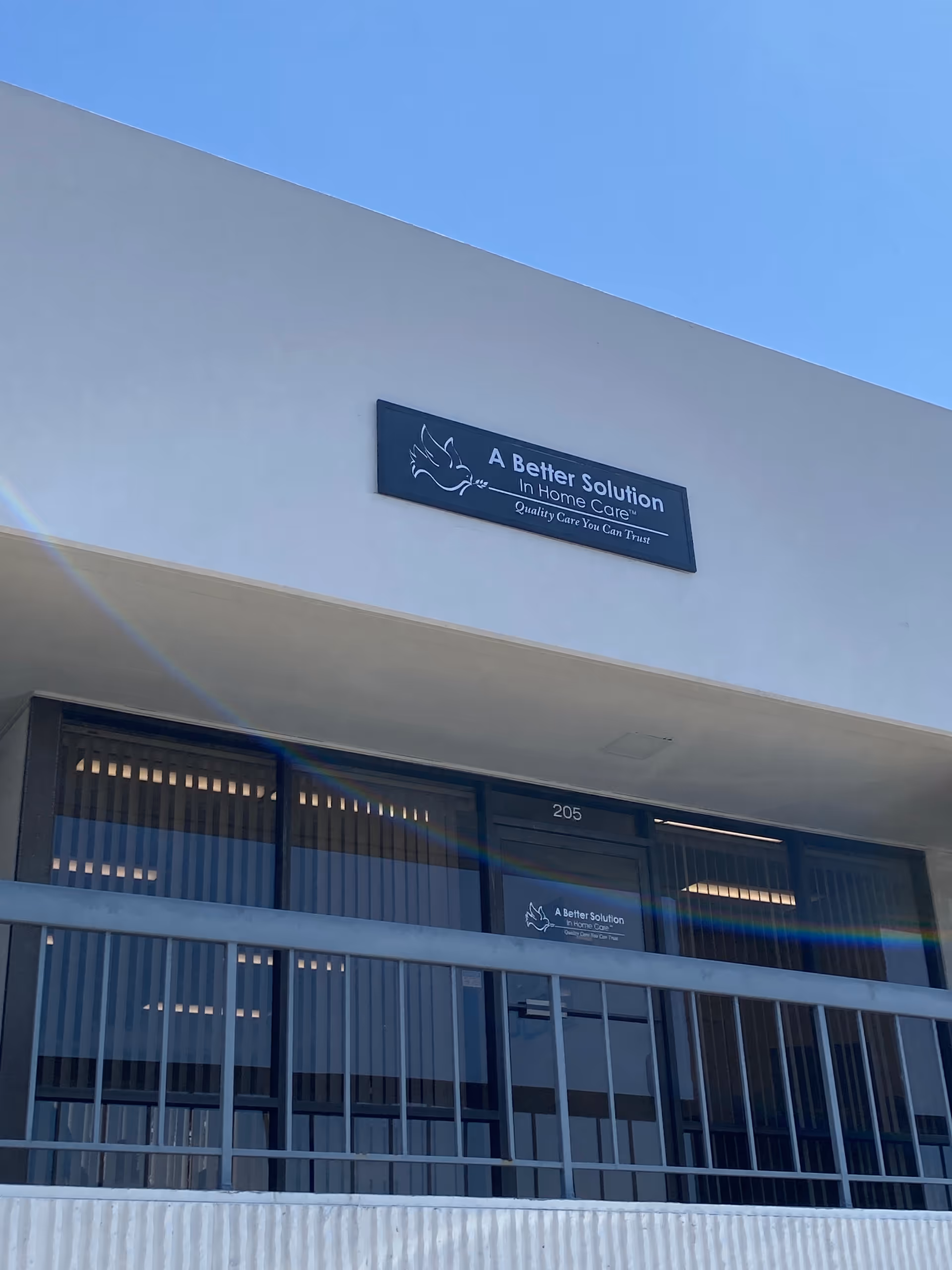 White building exterior with a blue sign reading 'A Better Solution In Home Care' above doors.