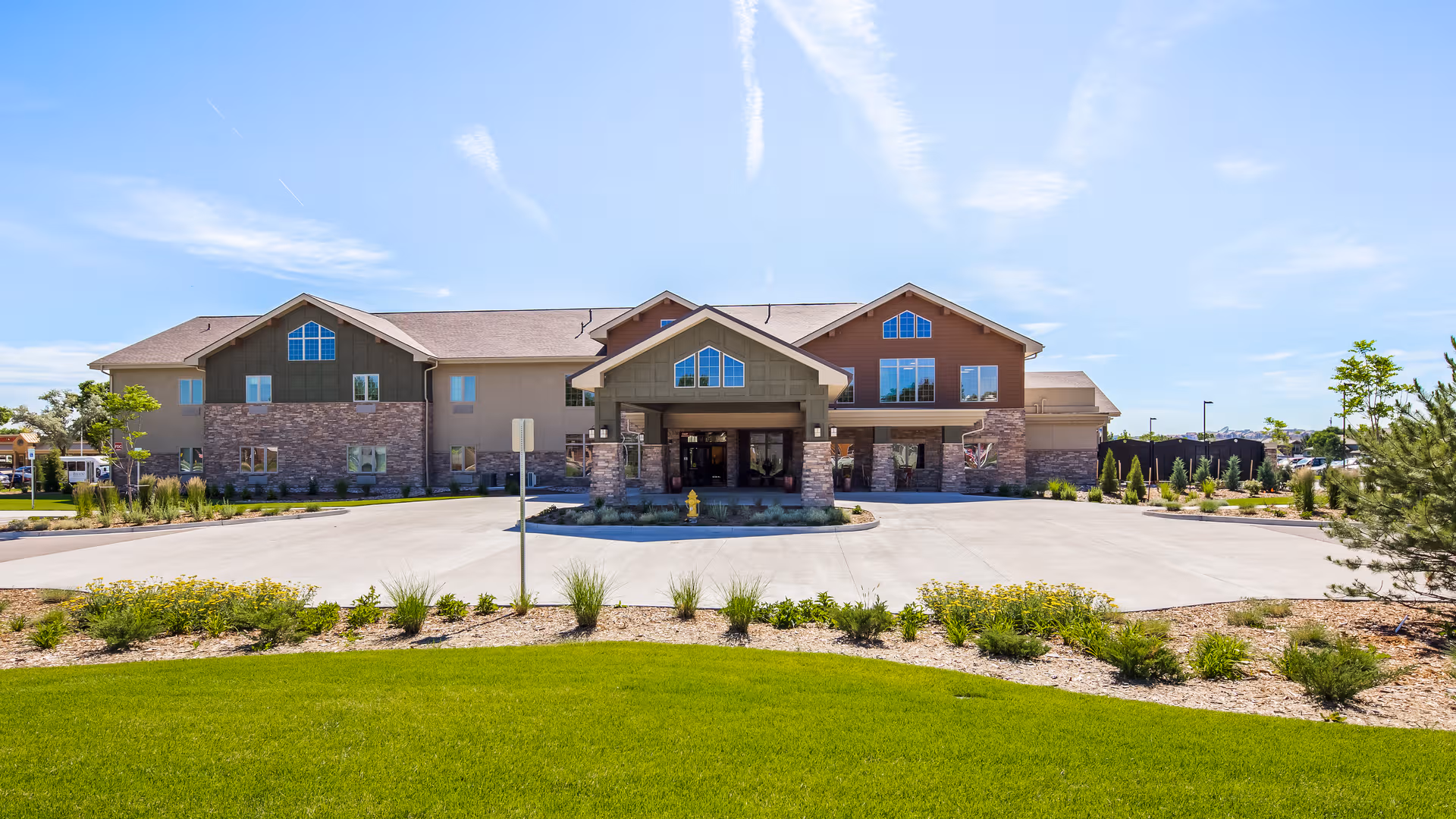 Front exterior view of Legend of Broomfield senior living facility with landscaped entrance.