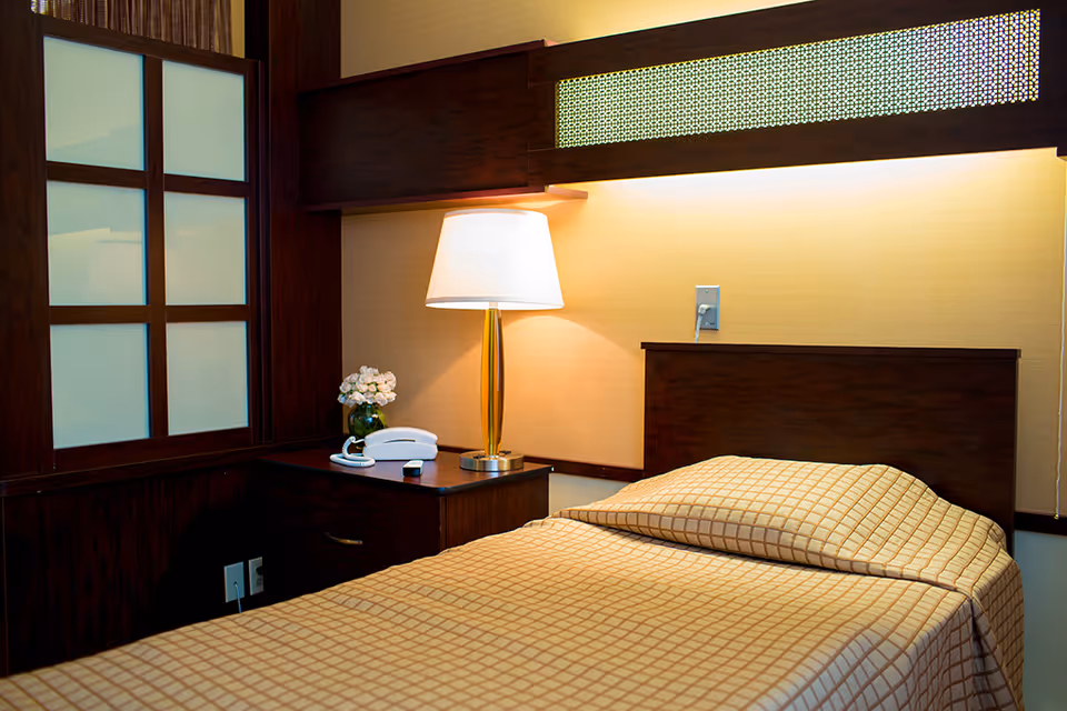 A neatly made bedroom featuring a wooden headboard, nightstand, lamp, and checkered bedding.