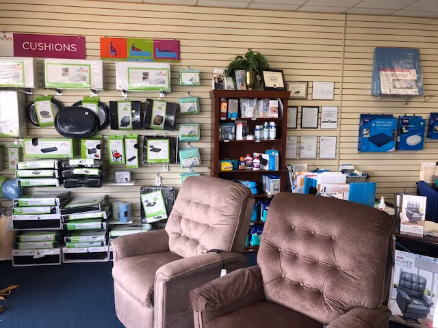 Interior display area with two brown recliner chairs and shelves of cushions and medical supplies.