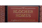 Brick exterior with a maroon BLOCHER HOMES sign mounted on the wall.