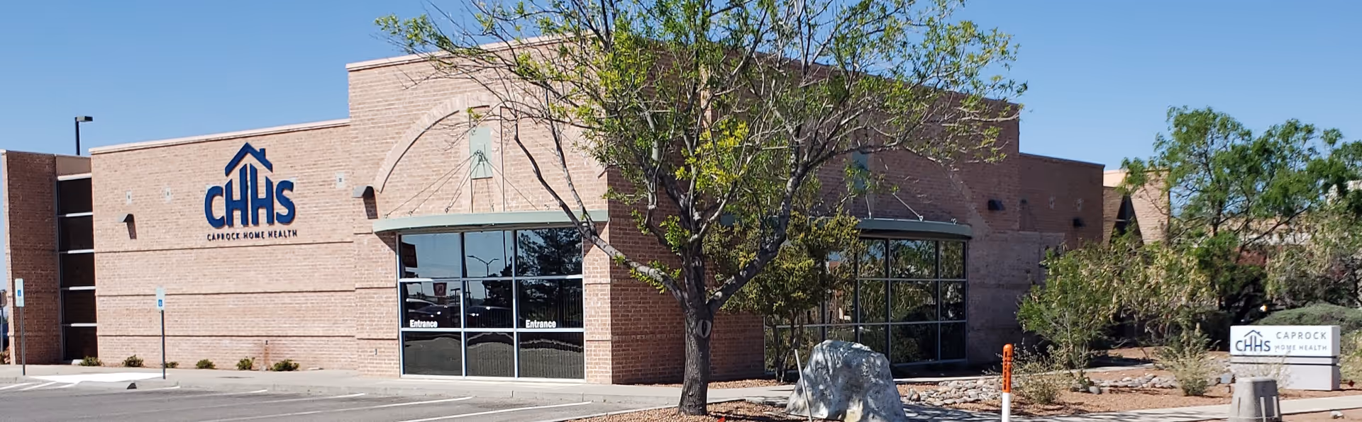 Brick Caprock Home Health Services Inc building with glass doors and trees in front.