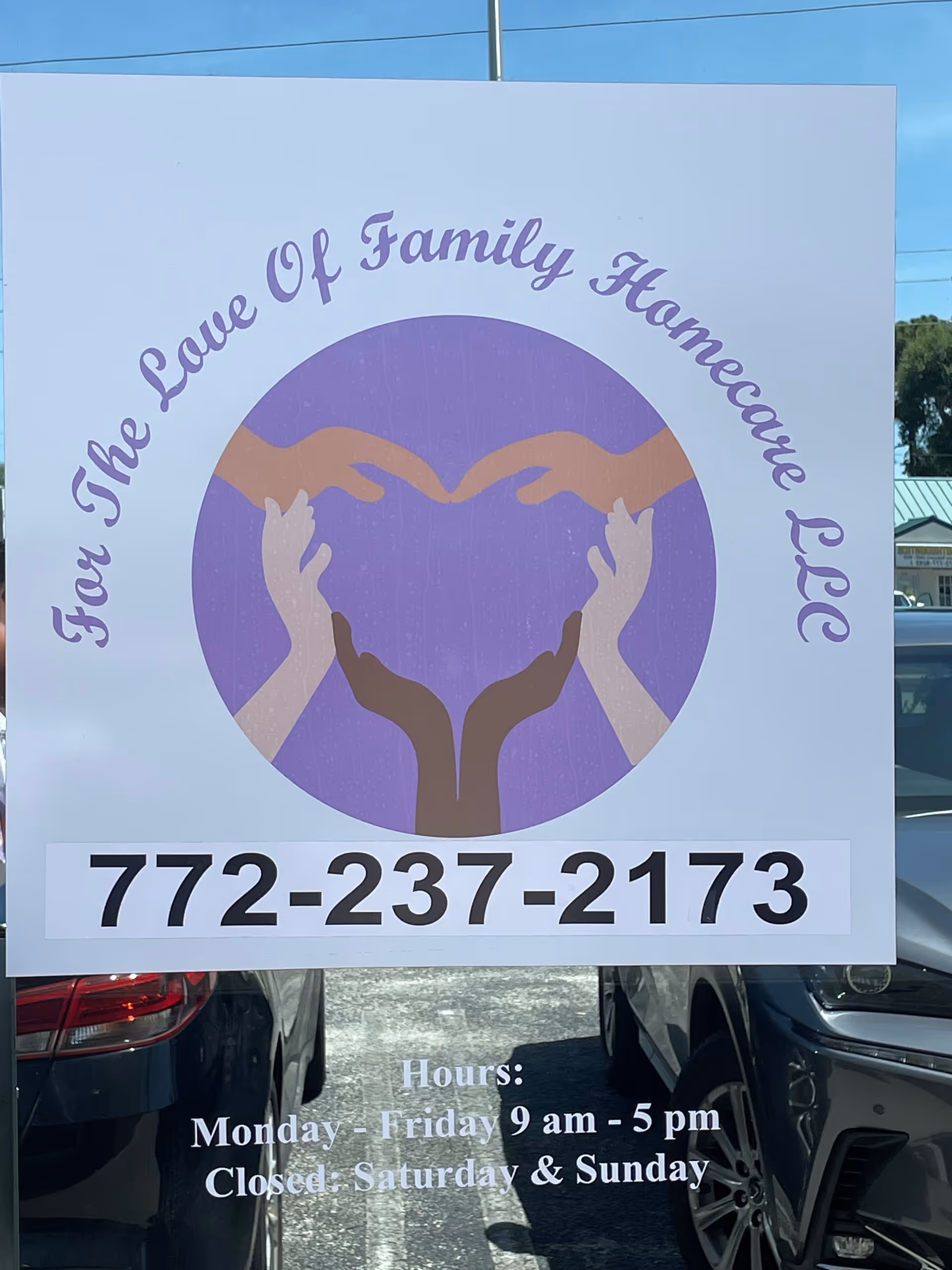 Large white sign with purple logo and phone number for For the Love Of Family Homecare.