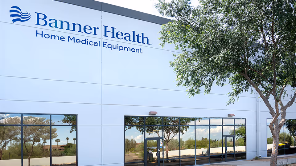 White building exterior displaying Banner Health Home Medical Equipment sign, with trees