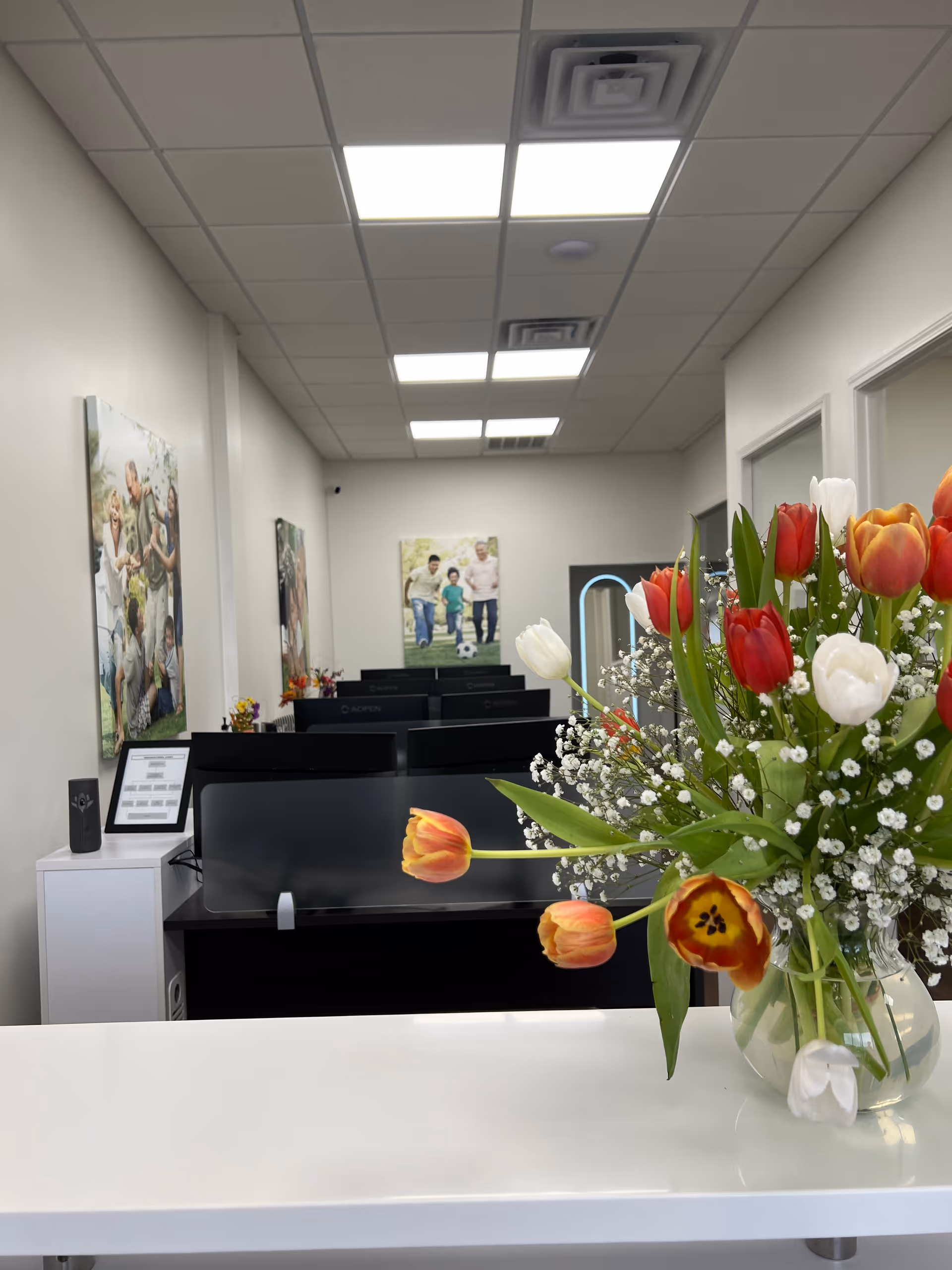 Reception area of a facility with computers, flowers, and wall photos.