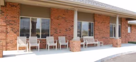 Exterior of Brookdale Pinnacle with brick walls and white chairs lined along the entrance.