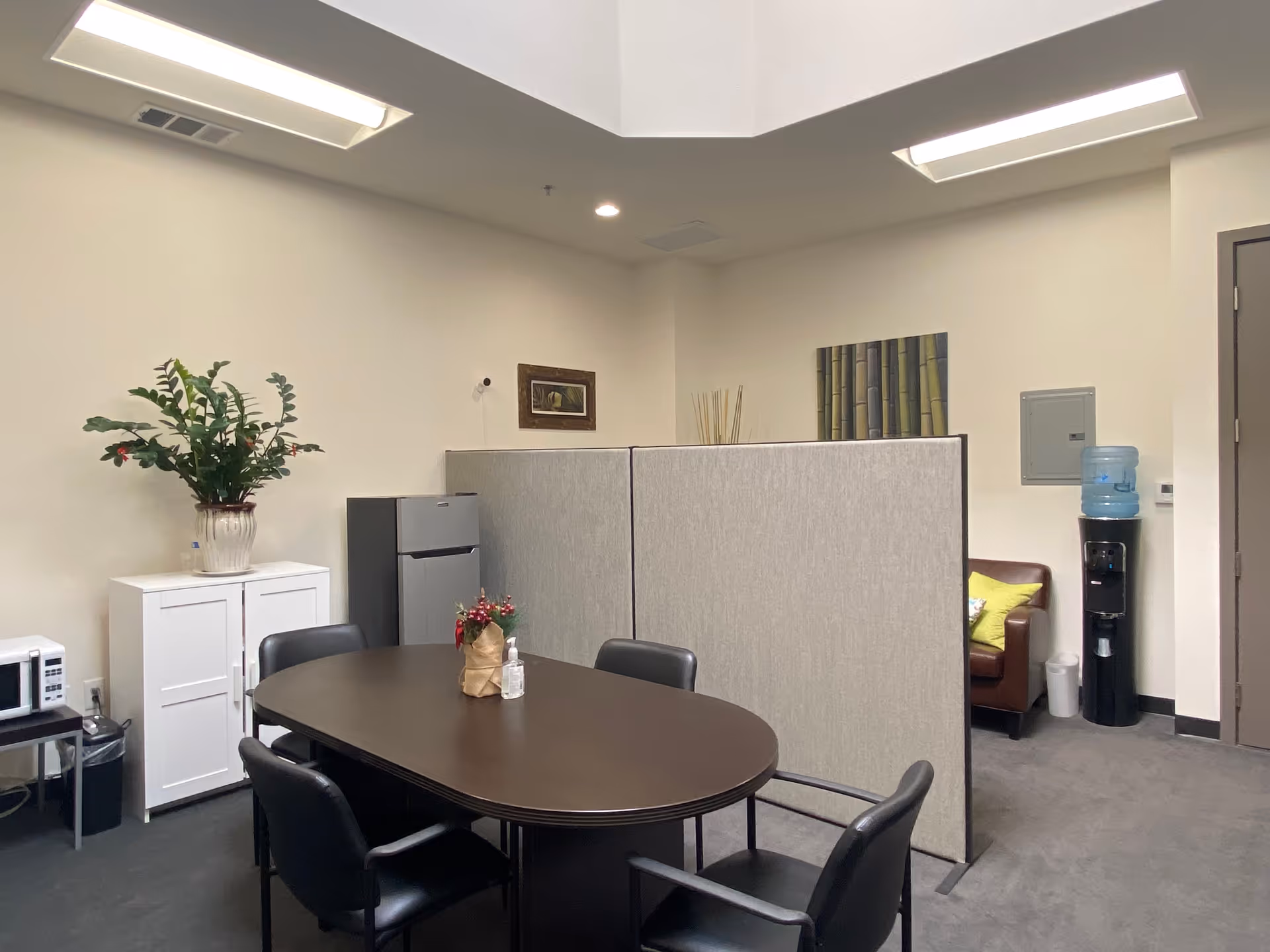 A small interior meeting and dining area with a round table, chairs, and partition panels.