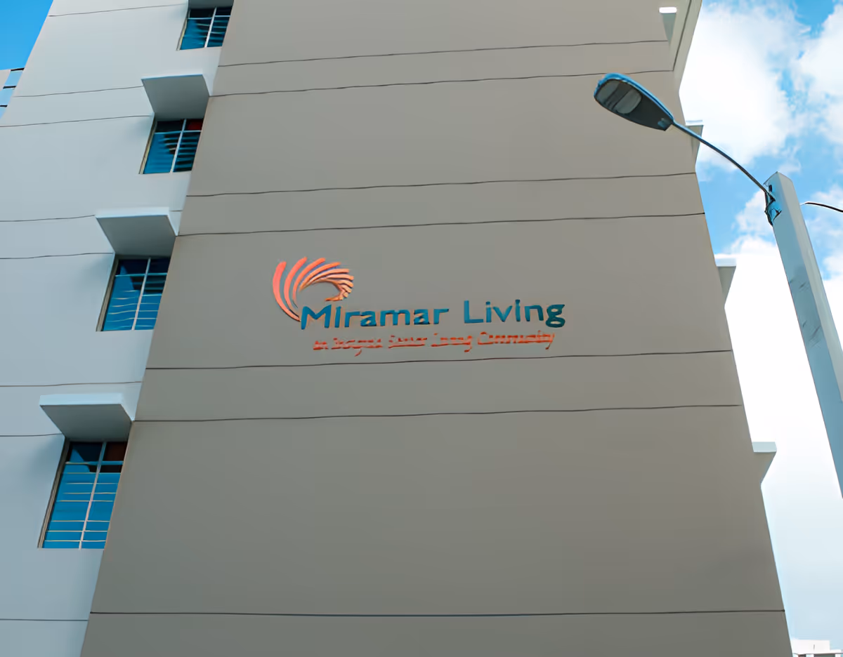 The exterior facade of Miramar Living, featuring a modern design with large windows and a prominent sign.