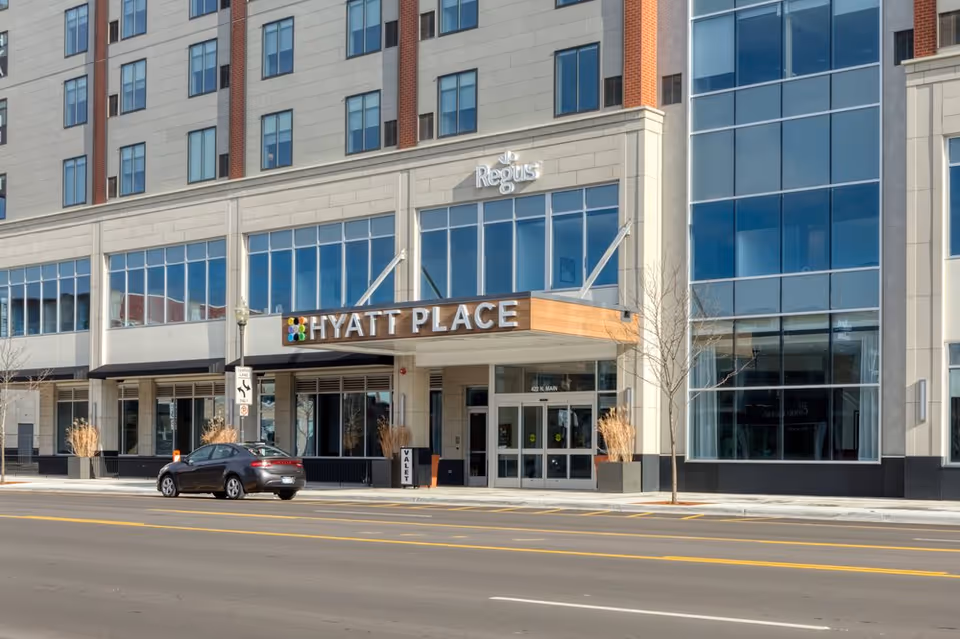 Exterior view of a modern building with Hyatt Place entrance along a city street.