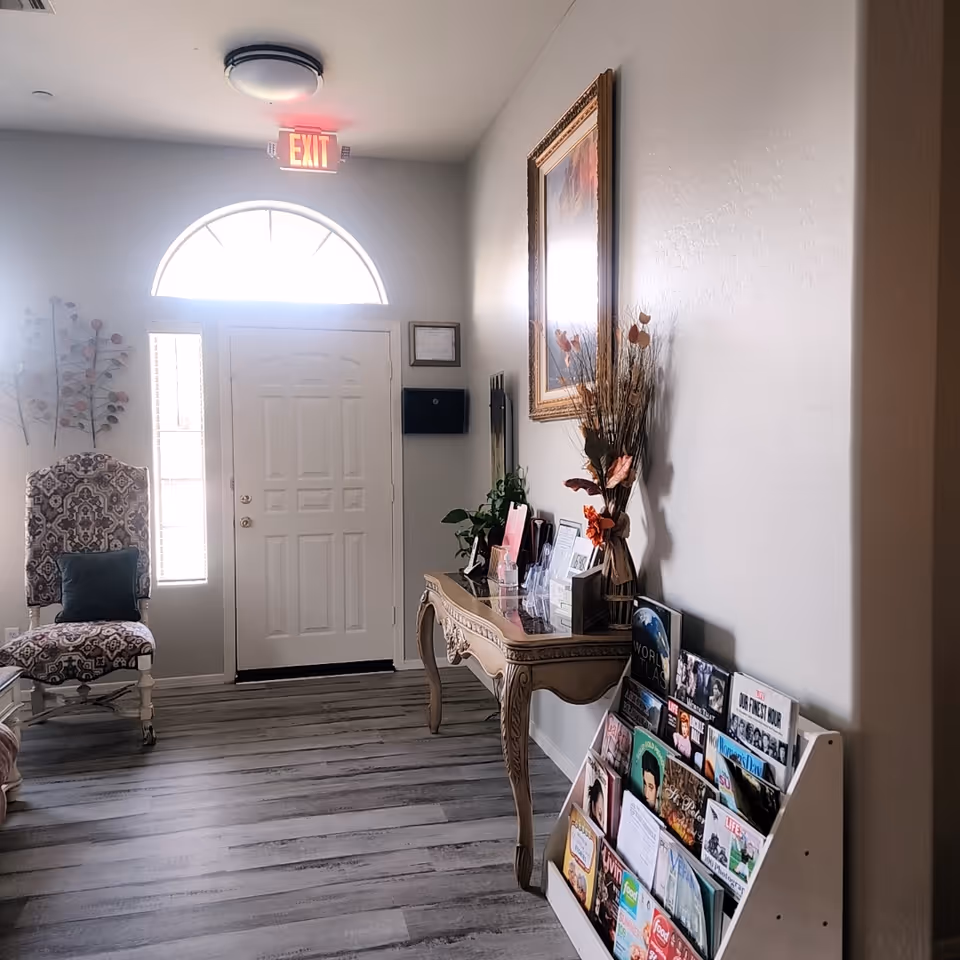 Entrance lobby of AMG Quality Care with a decorative chair, console table, and magazine rack.