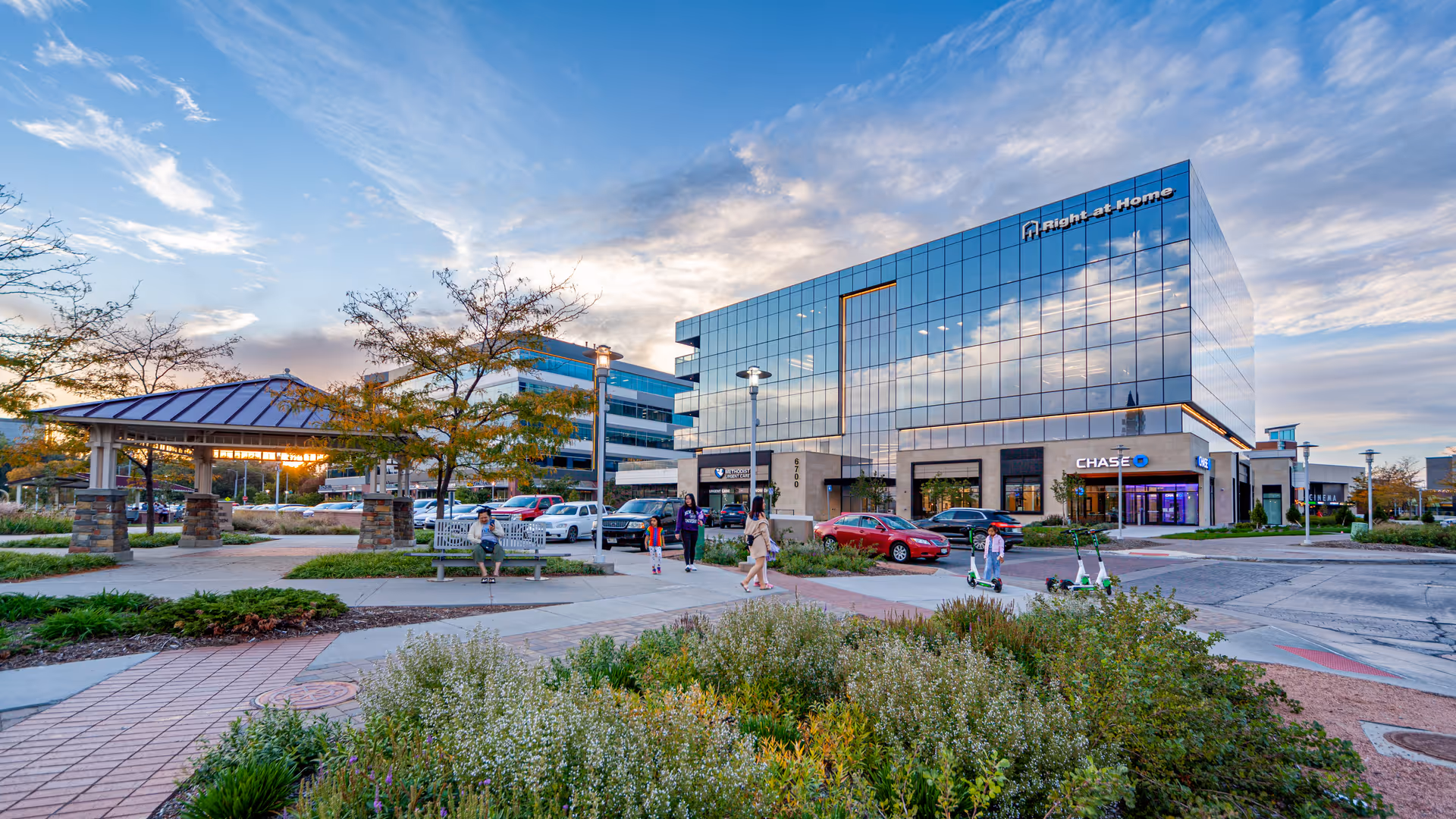 Modern glass-front building with Right at Home signage and people outside.