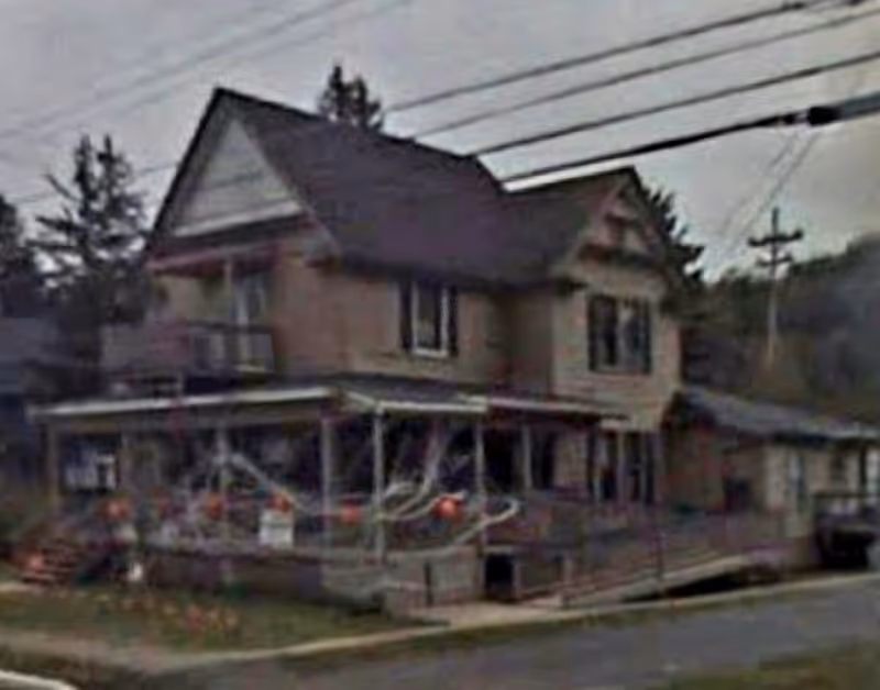 Two-story house-style senior living facility with a front porch and railing.