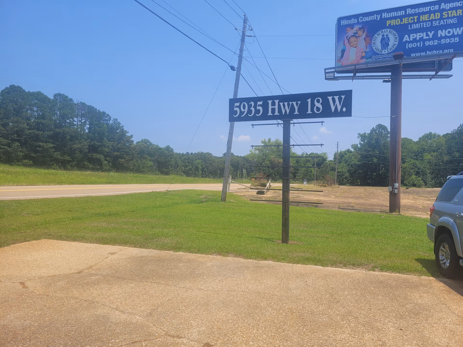 Roadside scene with a highway sign, billboard, and grassy area.