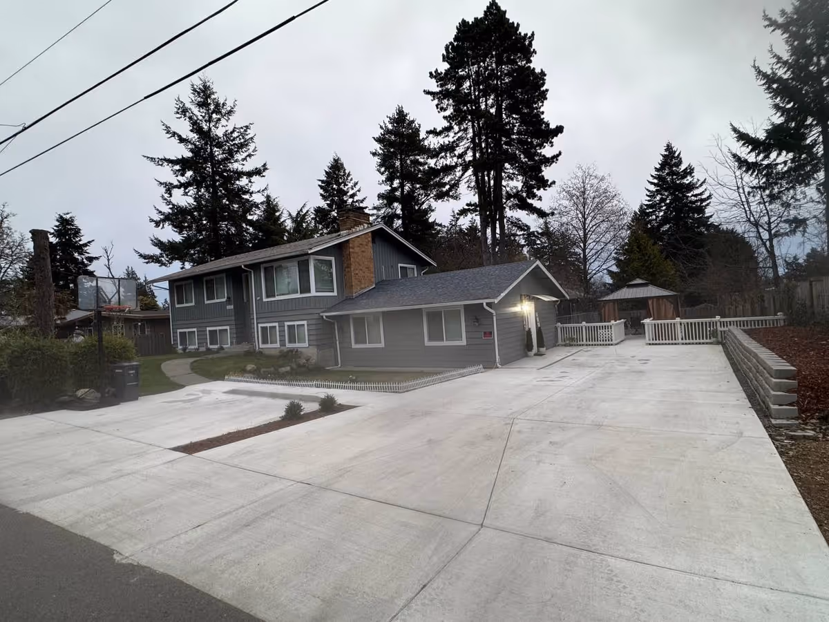 Exterior view of Bright Care AFH DesMoines LLC building with driveway and surrounding trees.