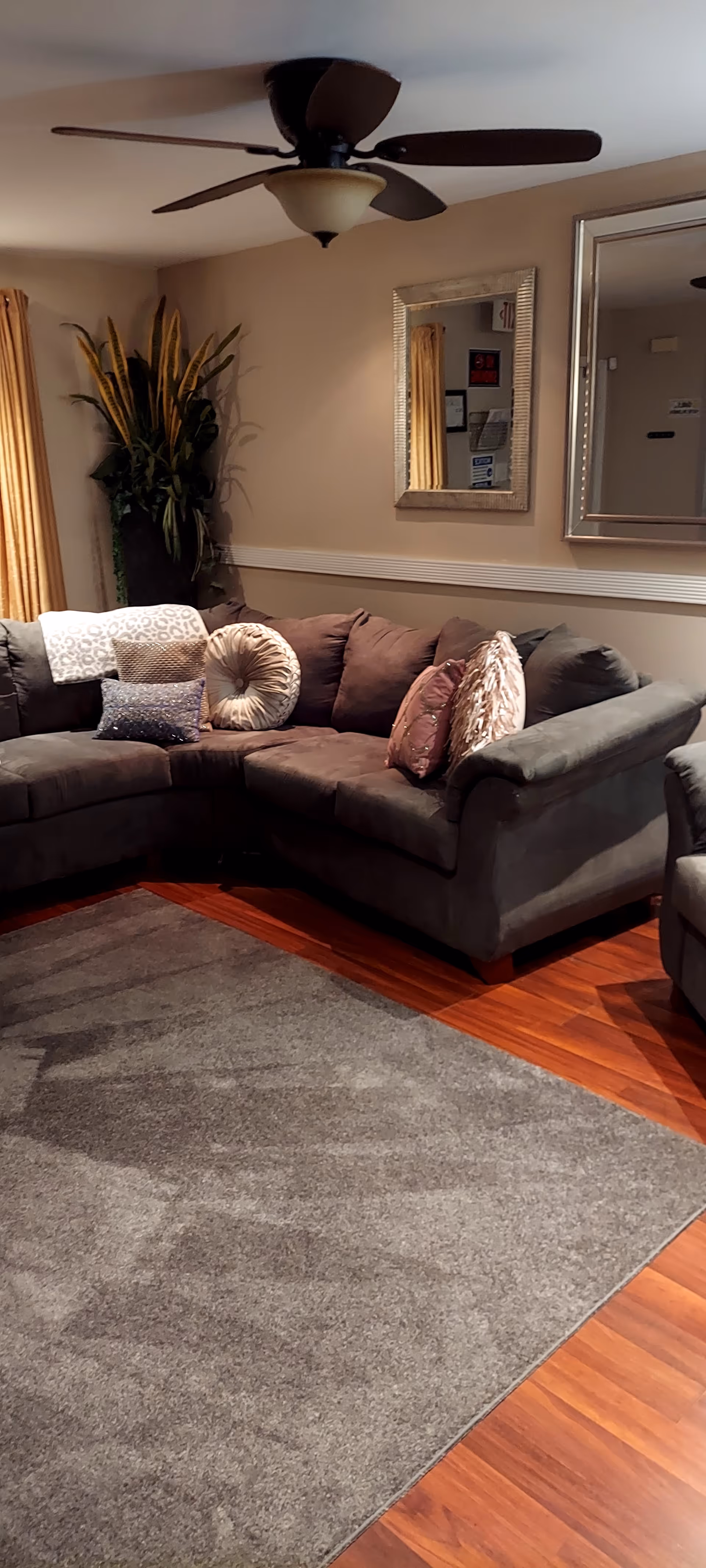 Cozy indoor living room at Maude Manor Assisted Living with sectional sofa and mirrors.