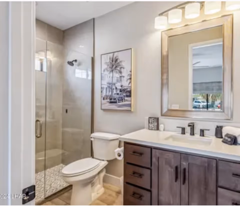 Modern bathroom in a senior living facility with glass shower, toilet, and vanity.