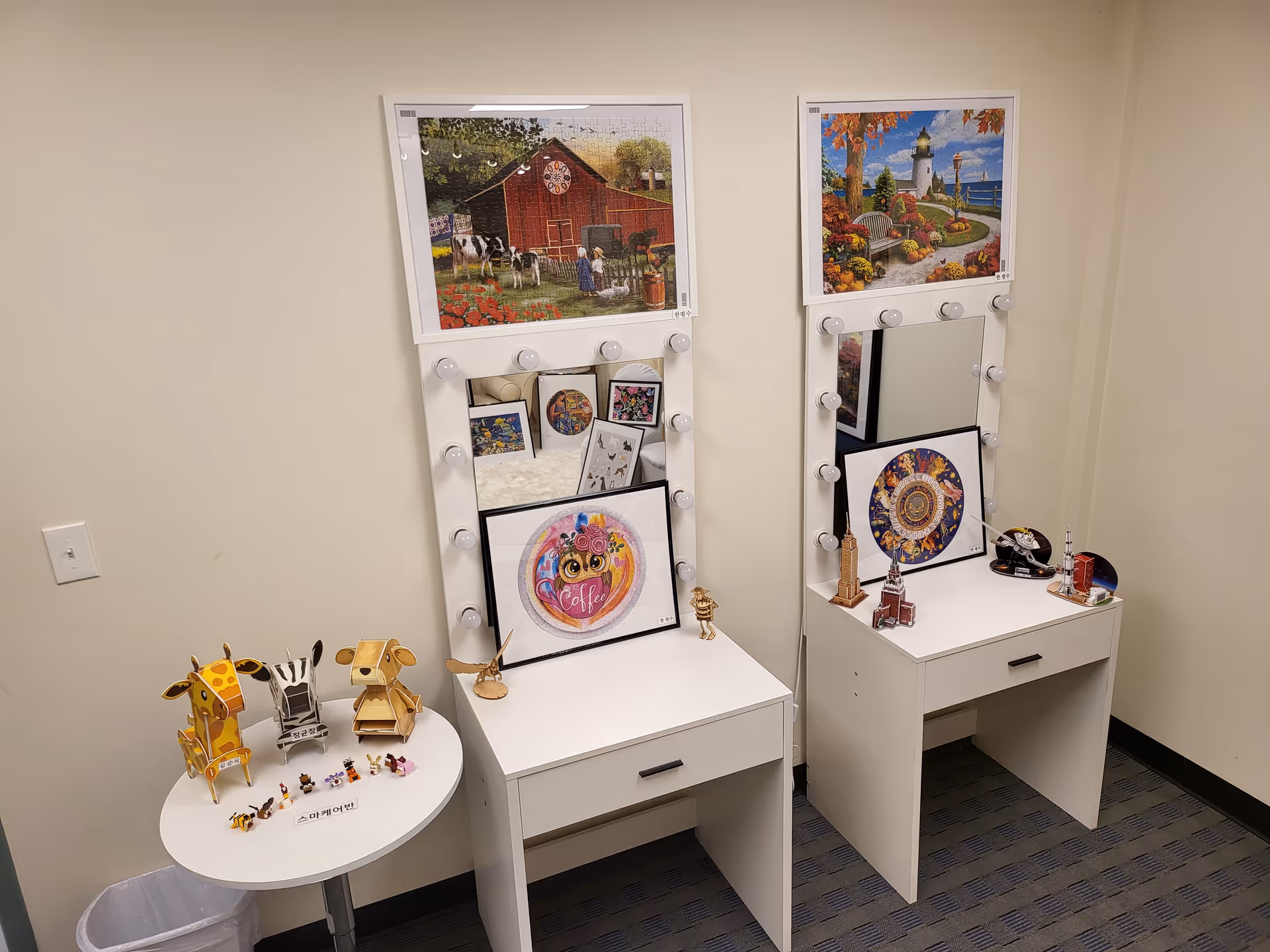 Two white vanity desks with lighted mirrors and framed artwork in a small, cozy interior.