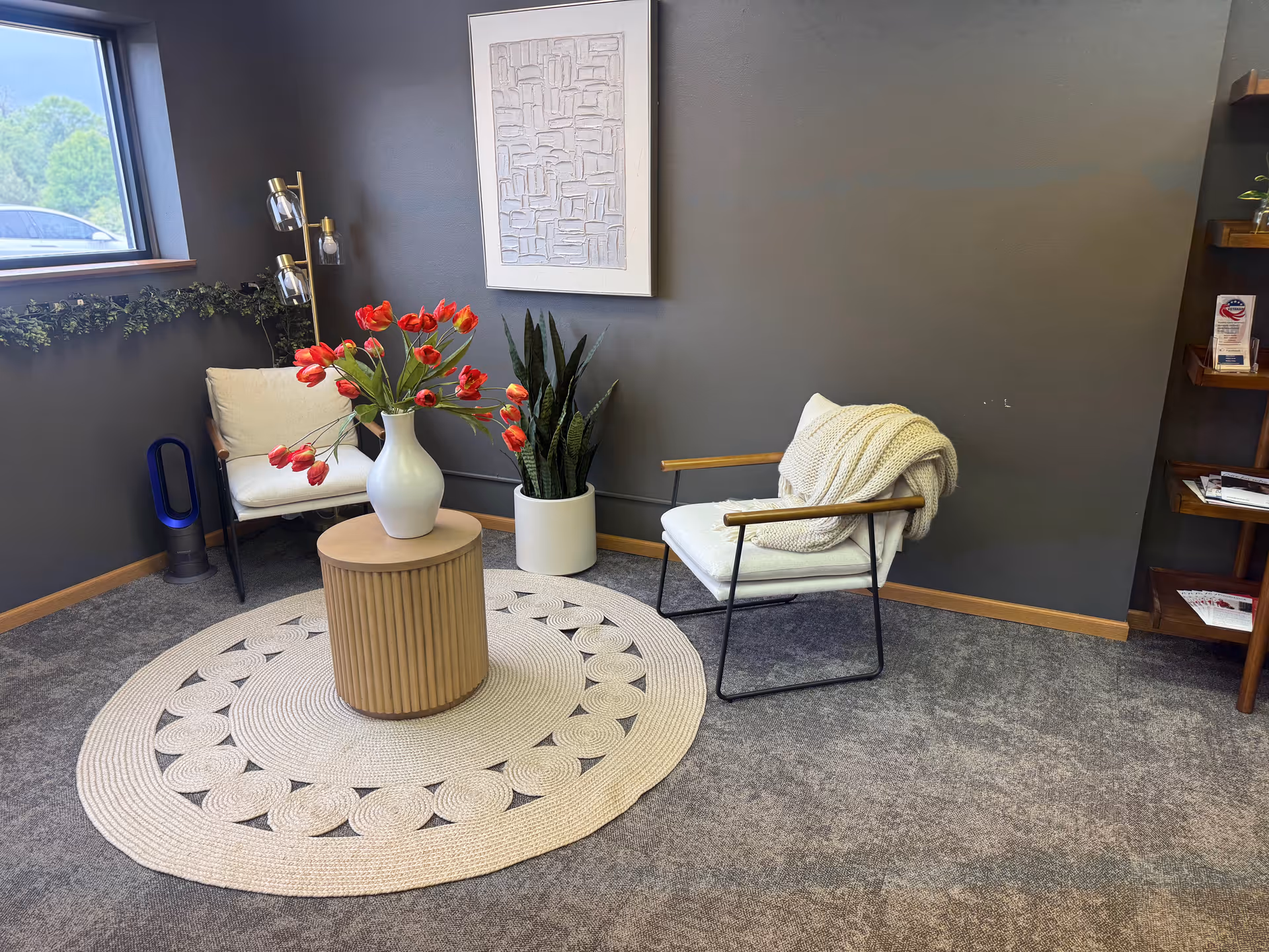 Modern lounge area with two chairs, a round woven rug, and potted plants.