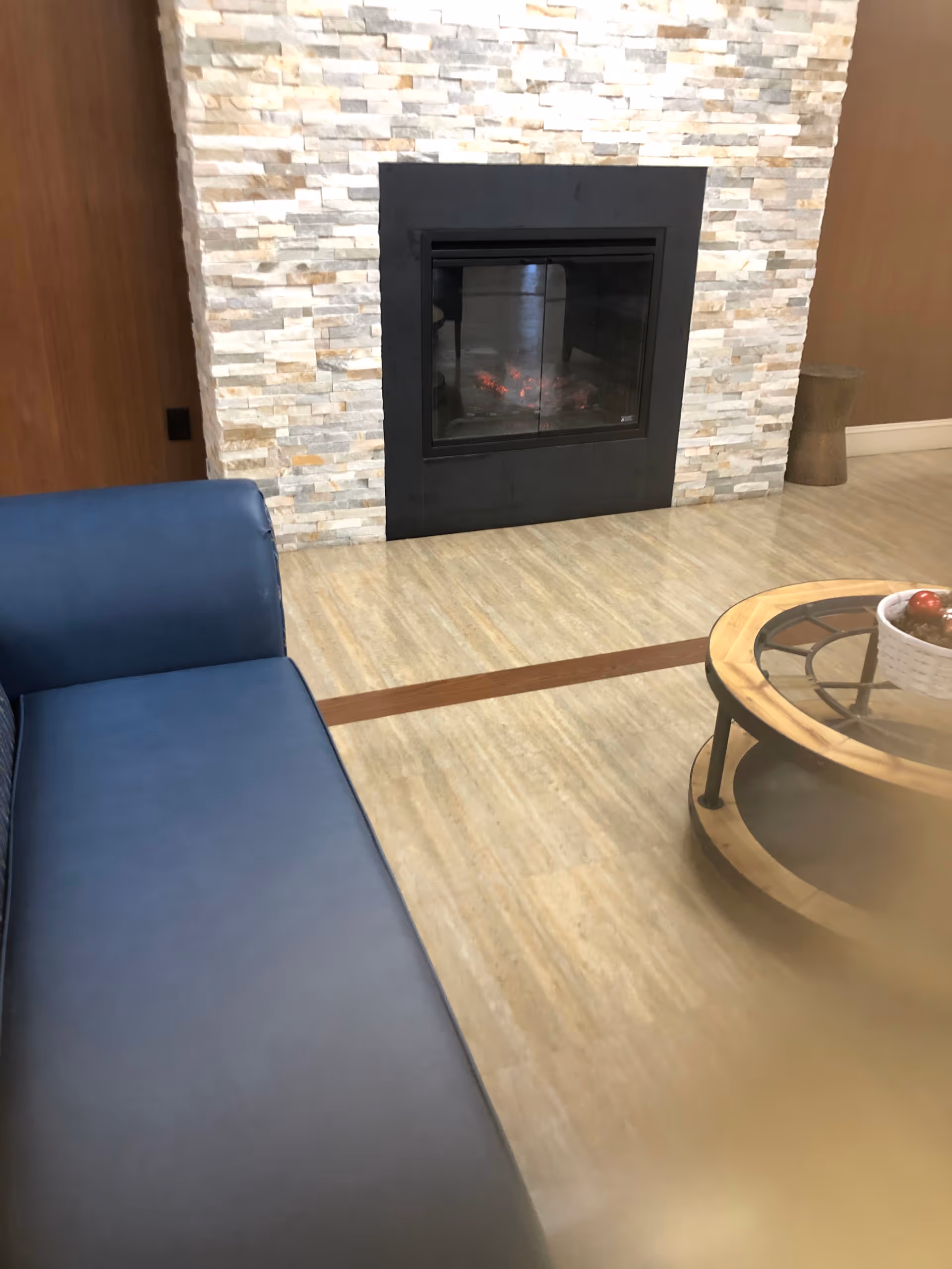 Cozy indoor living area with a stone fireplace, blue seating, and round coffee table.