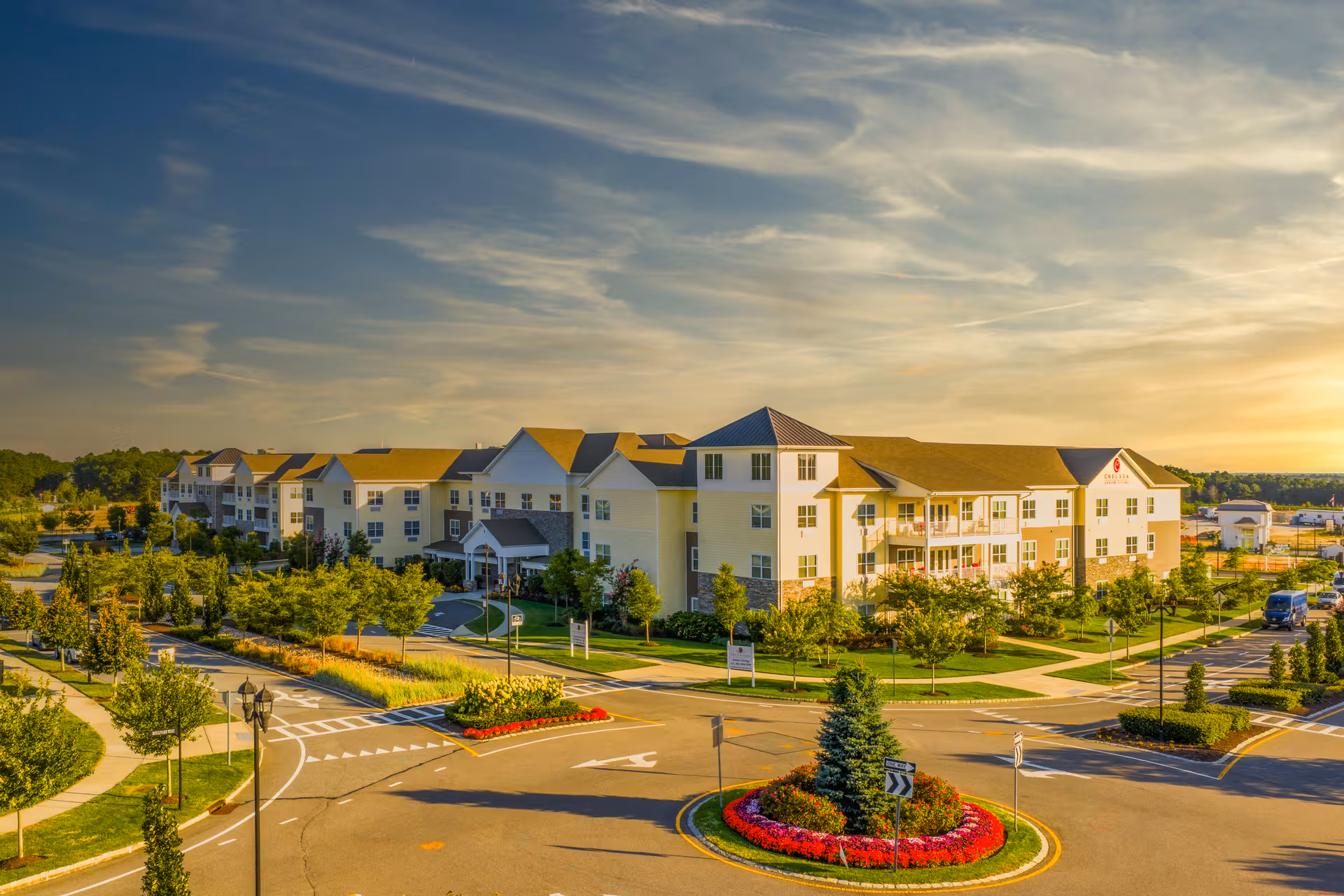 Exterior view of The Chelsea at Brookhaven, a cream-colored senior living building with landscaped grounds.