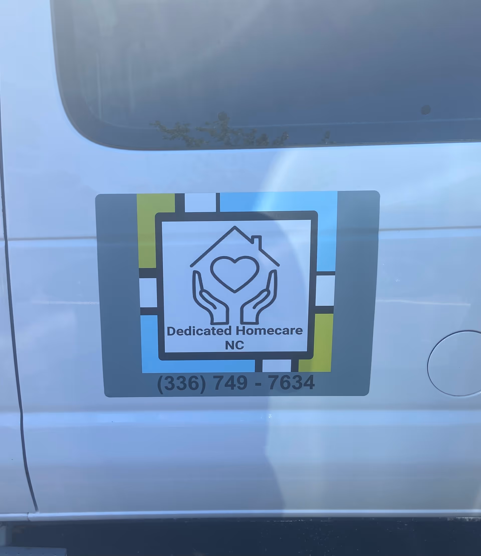 Exterior of van shows Dedicated Homecare NC logo sticker with phone.